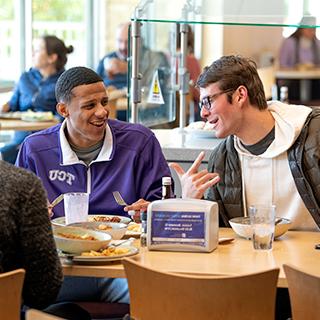 两名TCU男学生在校园主餐厅共进午餐时开怀大笑